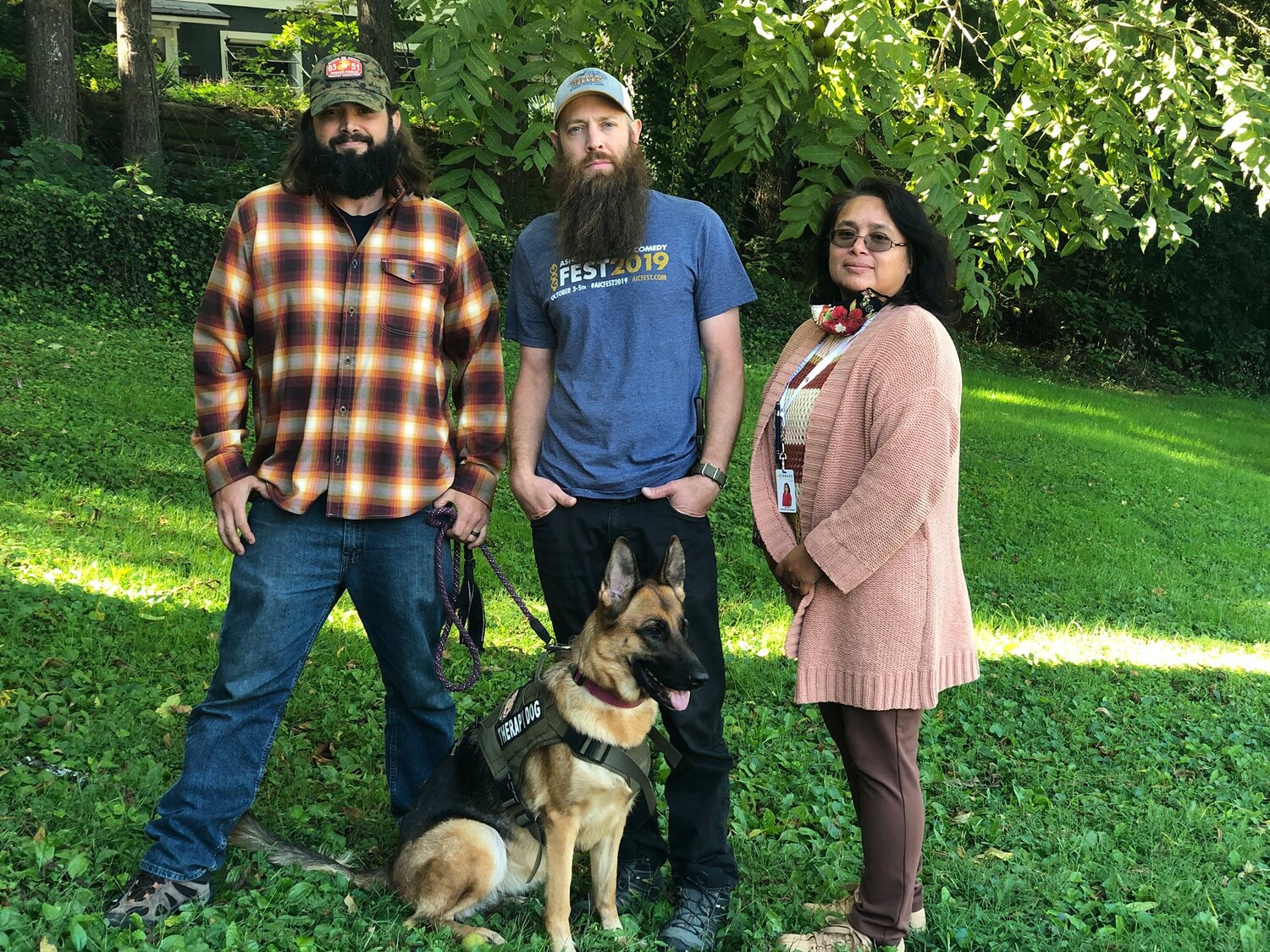 Veteran Stephen Coffee standing outside with his service dog, and two VSC team members, all smiling together.

